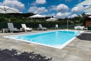 a swimming pool with white chairs and umbrellas at 'L Piasi in Cortanze