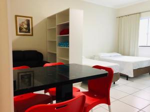 um quarto com uma mesa e cadeiras vermelhas e uma cama em Chemin Suites em Balneário Camboriú