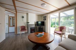 - un salon avec une table, des chaises et une télévision dans l'établissement 26, gelegen in het bosrijke Oisterwijk met privé tuin!, à Oisterwijk