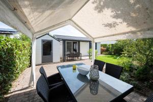 un patio con mesa y sillas bajo un pabellón en 26, gelegen in het bosrijke Oisterwijk met privé tuin!, en Oisterwijk