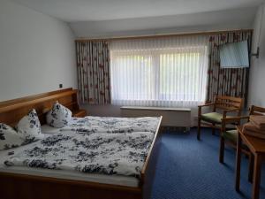 a bedroom with a bed and a chair and a window at Derentaler Hof in Derental