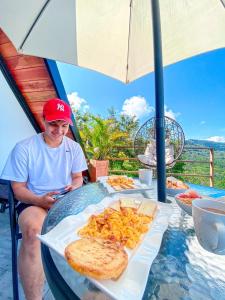 a man sitting at a table with a plate of food at Glamping San Pedro in San Gil