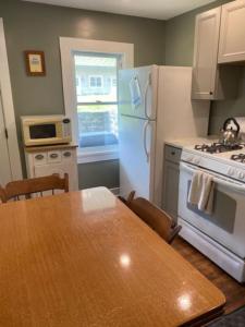 a kitchen with a table and a white refrigerator at Blueberry Cottage Lake Champlain in Plattsburgh