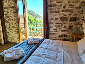 a bed in a room with a stone wall at El Hilo de los Sueños in Navatalgordo