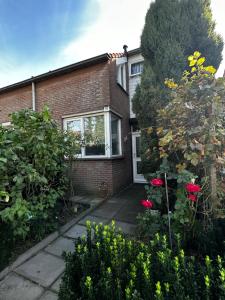 a brick house with a garden with roses at Room in Oss in Oss