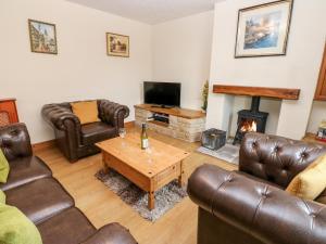 a living room with leather furniture and a fireplace at 1 Victoria Cottages in Bishop Auckland