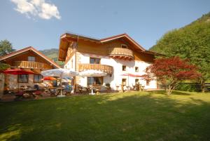 una casa con tavoli e ombrelloni in un cortile di Frühstücks- & Apartmenthaus Maislau a Rauris