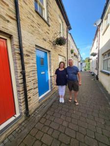 a man and a woman standing next to a building at Stunning seaside town cottage in Cardigan