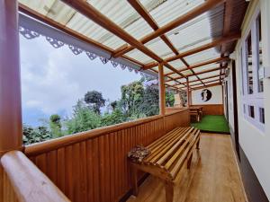 eine Holzterrasse mit einer Bank und einem Fenster in der Unterkunft Mandala Fram Stay in Darjeeling