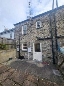 a brick house with a white door and a fence at Stunning seaside town cottage in Cardigan