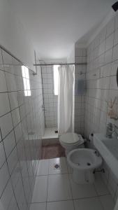 een wit betegelde badkamer met een toilet en een douche bij Departamento Céntrico Chaco in Resistencia