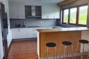 eine Küche mit weißen Schränken und einer Theke mit Barhockern in der Unterkunft CASA AREALBA Casa con piscina muy cerca de las playas de San Xurxo y Doniños in Ferrol