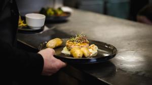 a person holding a plate of food on a counter at Astenturm Hotel in Winterberg