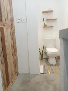 uma casa de banho com um WC e uma porta de madeira em IZAVA LODGE em Rodrigues Island