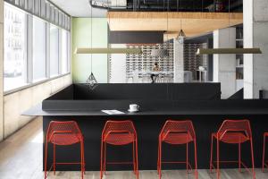 a kitchen with a black counter and red stools at Boro Hotel in Queens