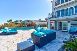 a patio with blue furniture in front of a building at Oceanfront Pool House 7 Bedrooms 7 Bath 2 Kitchens in Port Orange
