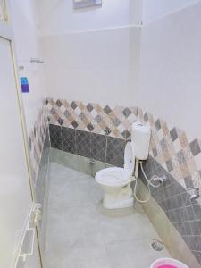 a bathroom with a toilet and a tiled wall at ALOK RESIDENCY in Satna