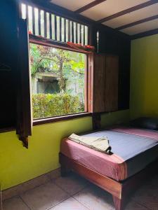 Cama pequeña en habitación con ventana en La Casa de Rolando, en Puerto Viejo