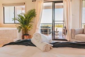 een slaapkamer met een bed met een bad en een balkon bij Cheerful family home with stunning views in Caloundra