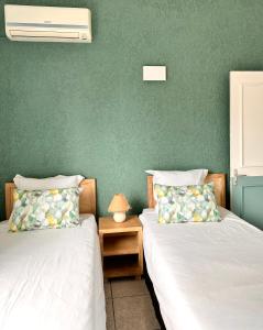 2 łóżka w pokoju z zieloną ścianą w obiekcie Azur - Résidence Le Dattier w mieście Flic-en-Flac