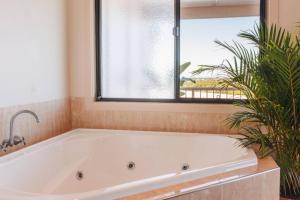 baño con bañera blanca y ventana en Cheerful family home with stunning views, en Caloundra