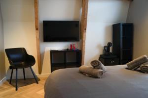 a bedroom with a bed with a television and a chair at Super de luxe privékamer op een toplocatie - Room 1 in Egmond aan Zee