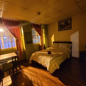 Schlafzimmer mit einem Bett, einem Tisch und einem Fenster in der Unterkunft Downtown in Quito