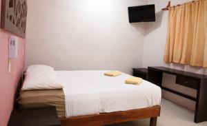 a small bedroom with a bed and a desk at Hotel Los Arcos Holbox in Holbox Island