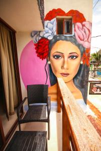 a balcony with a chair and a painting of a woman at Hotel Los Arcos Holbox in Holbox Island