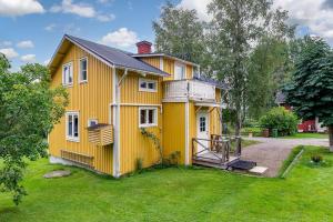 a yellow house with a porch and a yard at Mysigt hus utanför Järvsö in Järvsö