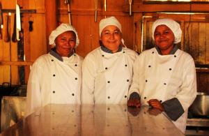 three chefs standing next to a table in a kitchen at El Remanso del Santuario in Camarones