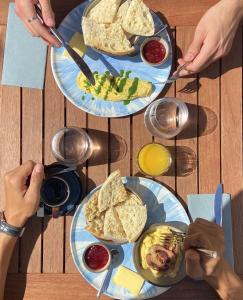 dos platos de comida en una mesa con personas sosteniendo utensilios en Le Maje Hostel, en Montpellier