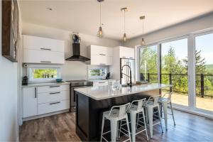 a kitchen with white cabinets and a large island with bar stools at Chalet Alpine by Tremblant Platinum in La Conception