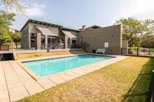 a swimming pool in front of a house at Lea's Furnished Apartments - Dainfern in Sandton