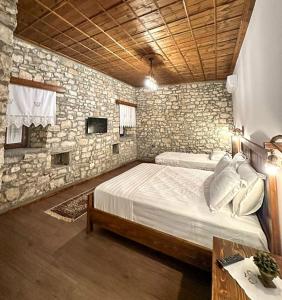 a bedroom with a large bed and a stone wall at Koroni Boutique Hotel in Berat