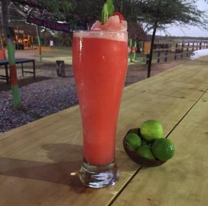 a drink sitting on a table next to a bowl of limes at El Remanso del Santuario in Camarones