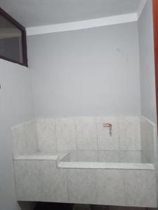 a white bathroom with a tub and a faucet at DEPARTAMENTO CON 3 DORMITORIOS in Huánuco