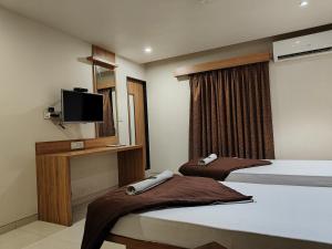 a hotel room with two beds and a flat screen tv at HOTEL SAHYOG & ROOMS in Surat