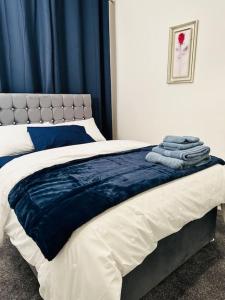 un letto con lenzuola e asciugamani blu e bianchi di Bespoke 2 Bedroom Apt Derby City a Derby