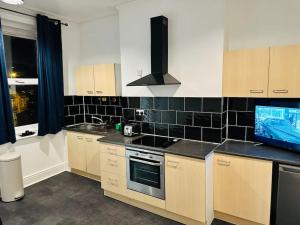 a kitchen with black and white tiles on the wall at Bespoke 2 Bedroom Apt Derby City in Derby