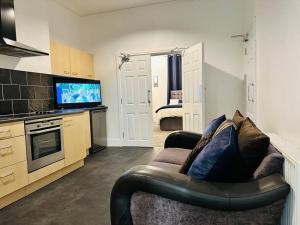 a living room with a couch and a tv in a kitchen at Bespoke 2 Bedroom Apt Derby City in Derby