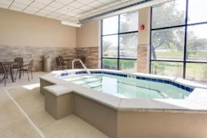 a large jacuzzi tub in a room with windows at Hotel Lotus Kansas City Merriam in Merriam