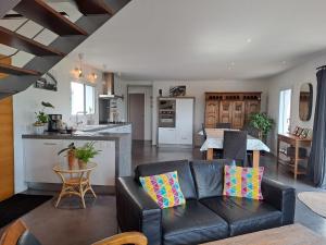 a living room with a couch and a kitchen at Maison traditionnelle et moderne avec vue mer in Tréffiagat