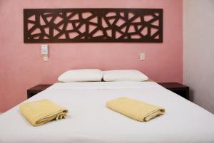 a bedroom with a white bed with two towels on it at Hotel Los Arcos Holbox in Holbox Island