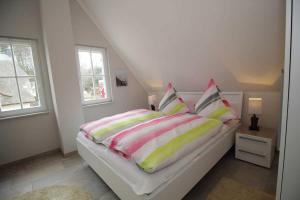 Schlafzimmer mit einem Bett mit bunter Bettwäsche und Kissen in der Unterkunft Reethaus Seeschwalbe in Glowe
