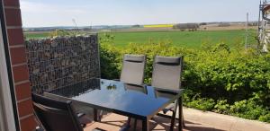 2 Stühle und ein Tisch auf einer Terrasse mit Blick auf ein Feld in der Unterkunft Ferienwohnung Kranichglück in Neddesitz