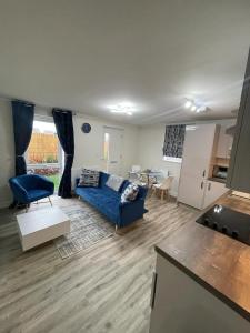 a living room with a blue couch and a kitchen at Luxurious Apartment in Brooklands in Milton Keynes