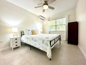 a bedroom with a bed with a ceiling fan and a window at Snug Harbour View Condo #5 in George Town