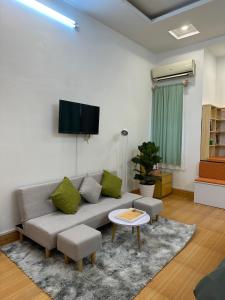 a living room with a couch and a tv on a wall at Đất Cảng Homestay in Hai Phong