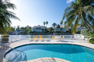 a swimming pool with palm trees and houses at Snug Harbour View Condo #2 in George Town